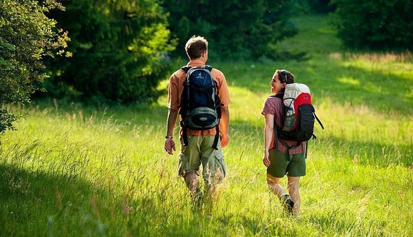 Zwei Wanderer gehen durch eine grüne Wiese in der Natur