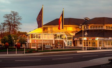Stadthalle mit europäischen und deutschen Fahnen bei Sonnenuntergang