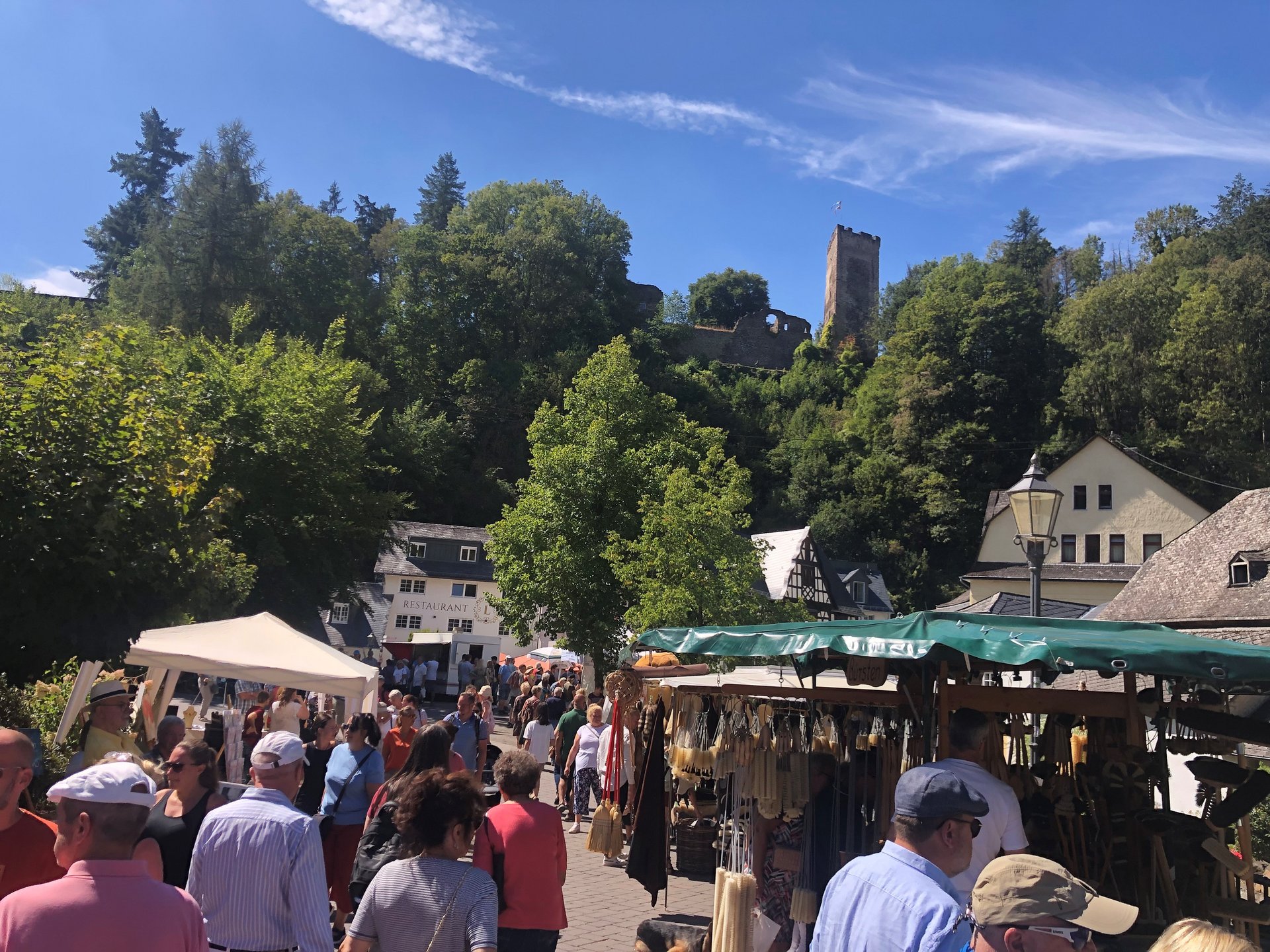 Menschenmenge auf einem Markt mit Burg im Hintergrund und blauen Himmel