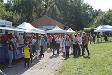Bunte Menschenmenge auf einem Markt mit verschiedenen Ständen und Zelten