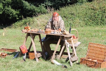 Ein Handwerker arbeitet im Freien mit verschiedenen Werkzeugen und Waren.