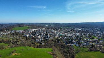 Panoramaansicht einer Stadt umgeben von Grün und Hügeln