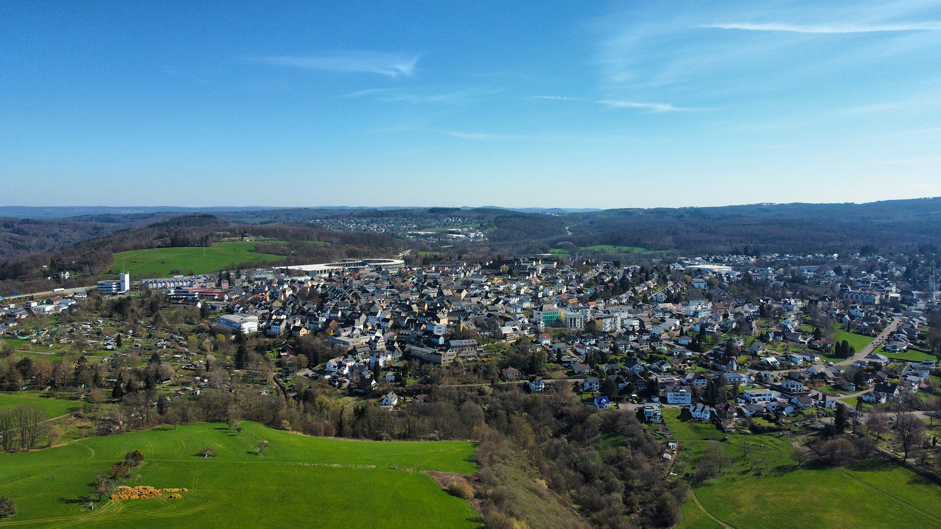Panoramaansicht einer Stadt umgeben von Grün und Hügeln